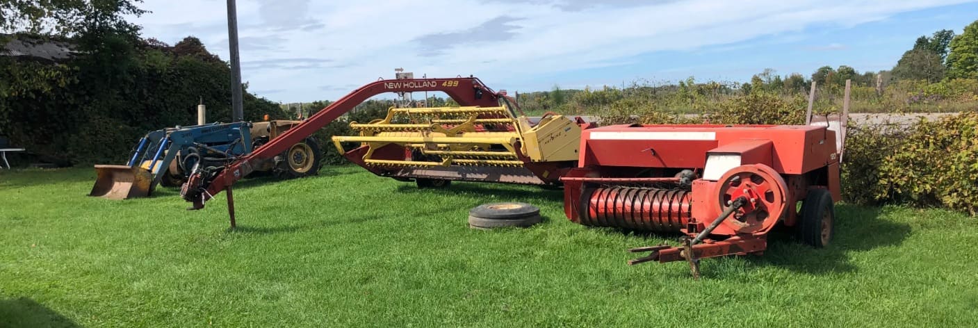A New Holland haybine and baler on the grass (photograph from the JMAC Auctions website)